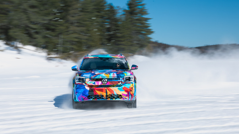 A 2027 Volkswagen Atlas covered in multicolor camo sliding through snow