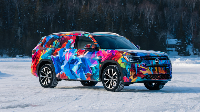 A front three-quarters of a 2027 Volkswagen Atlas covered in multicolor camo