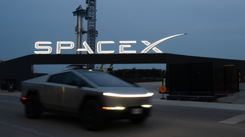 A Tesla Cybertruck drives in front of the SpaceX sign with Starship in the background on June 2, 2024 just days prior to launch.