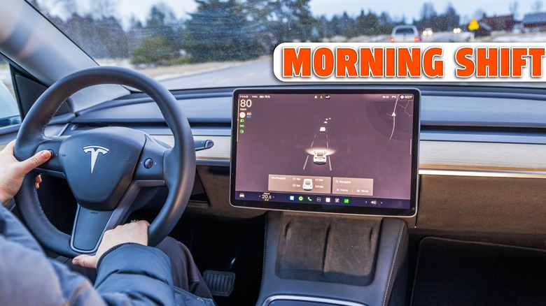 Woman driver holding steering wheel of Tesla Model X electric car with autopilot screen on road.