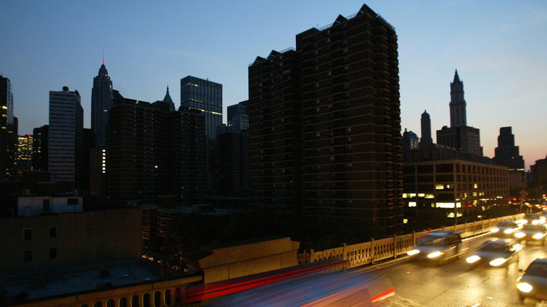 Cars head over the Brooklyn Bridge beside a blacked out New York City skyline August 14, 2003 during a power outage.