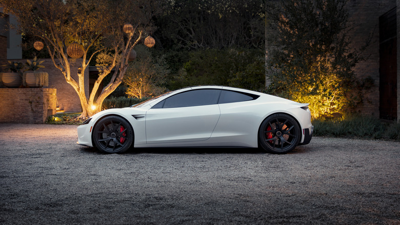 A white Tesla Roadster, seen in side view in a driveway