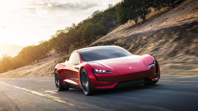 A red Tesla Roadster seen driving from the front