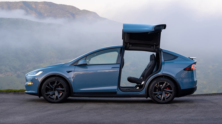Side view of a blue Tesla Model X with the doors open
