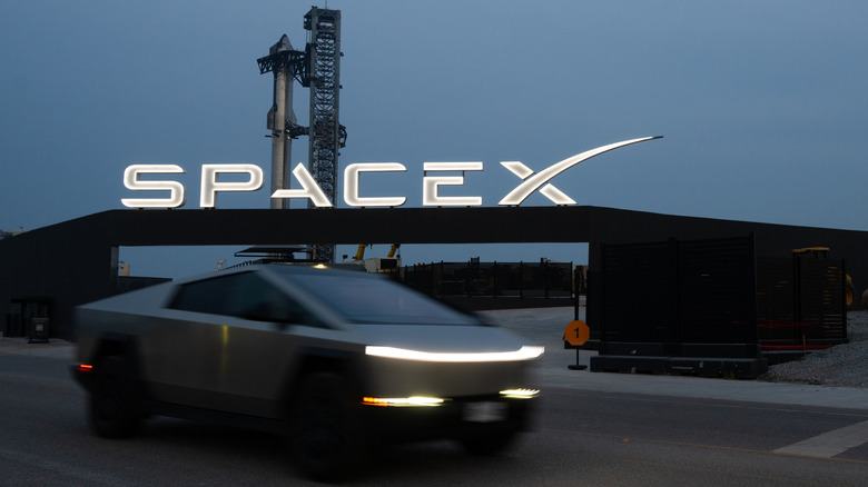 A Tesla Cybertruck drives in front of the SpaceX sign with Starship in the background on June 2, 2024 just days prior to launch.