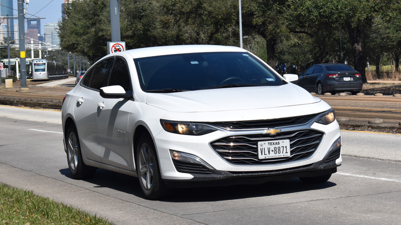 A white Chevy Malibu, cruising near Metro railway train tracks and Hermann Park.