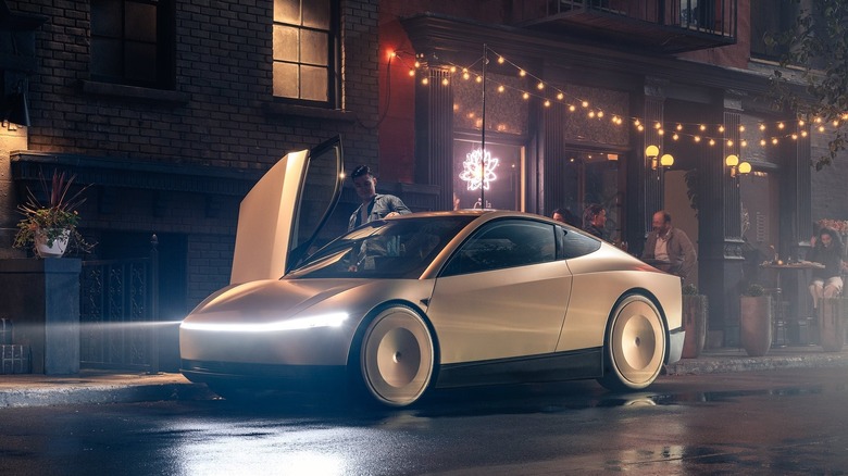Front three quarters shot of a gold Tesla Cybercab parked curbside at night with its headlight on outside a bar