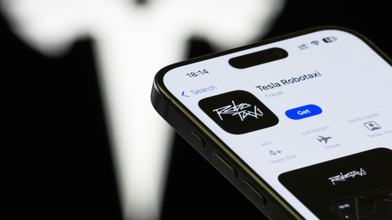 In this photo illustration, a smartphone displays the Tesla Robotaxi app page on the Apple App Store, with the Tesla logo visible in the background on September 4, 2025 in Chongqing, China.