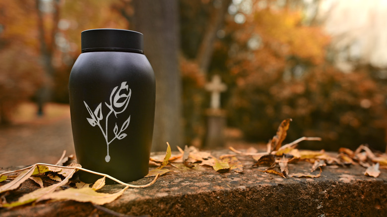 Funeral urn on grave stone with fall leaves