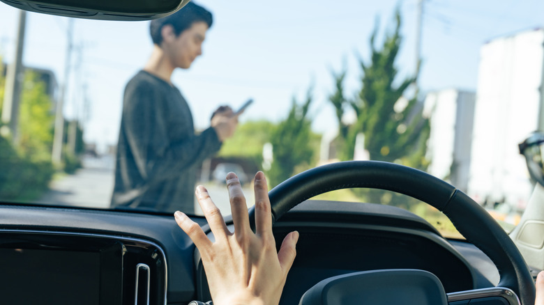 Photo showing a distracted pedestrian in front of a car