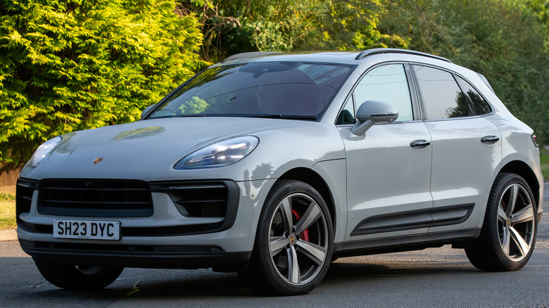 A white Porsche Macan driving down a road.