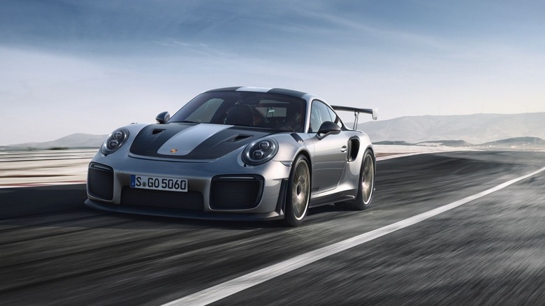 A silver and black 911 GT2 RS (991.2) accelerating down a sun-bleached racetrack.