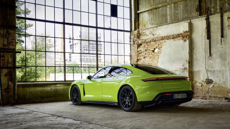 An Acid Green Porsche Taycan parked inside a cavernous industrial warehouse.