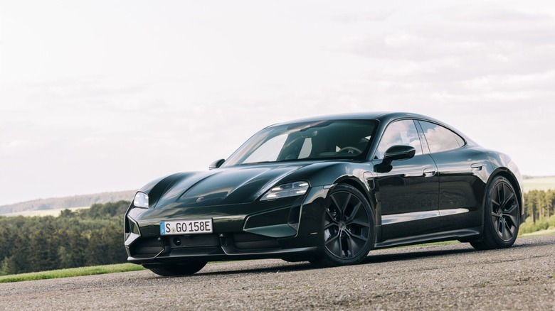 A dark Porsche Taycan Turbo sedan parked on a gravel surface.