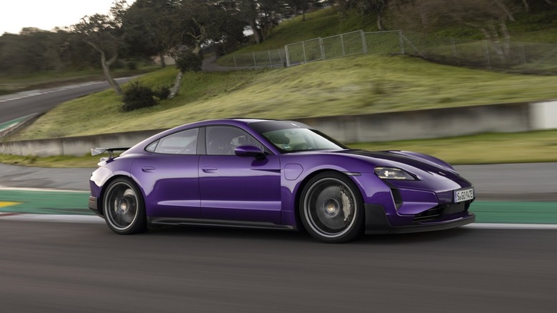 A vibrant purple Porsche Taycan Turbo GT driving through a racetrack corner.