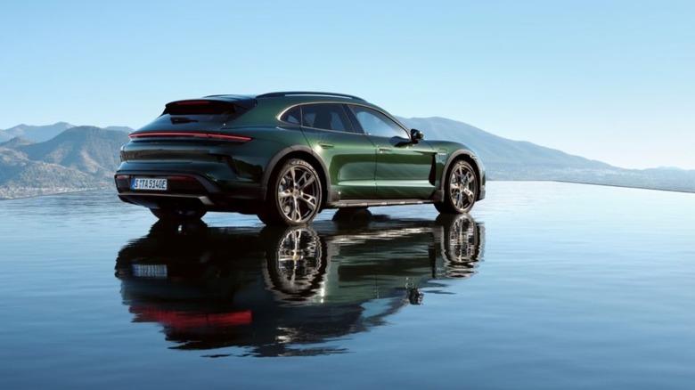 A dark Oak Green Metallic Porsche Taycan Turbo S Cross Turismo parked on a water-like reflective surface.