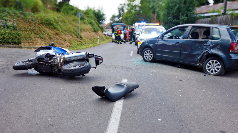 Motorcycle on the ground after an accident with cars in the background.