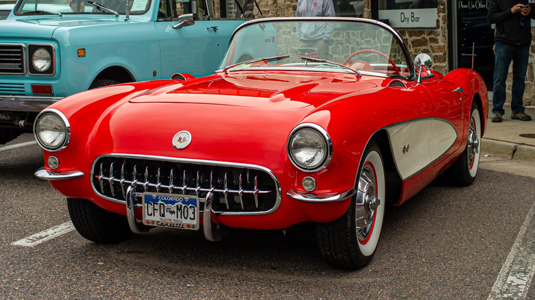 A 3/4 front-left view of a red and white 1957 Chevrolet Corvette parked at an antique car show