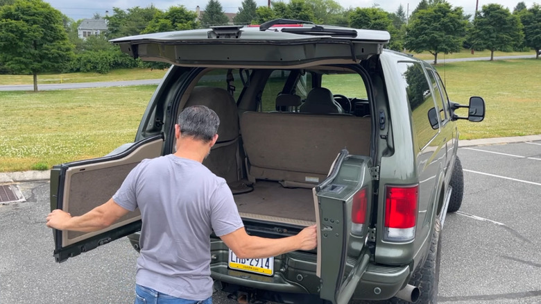 A man opening up the rear barn doors of a 2000 Ford Excursion