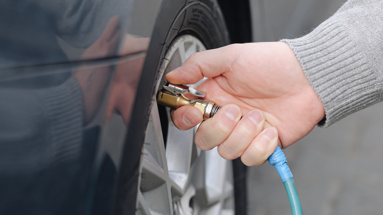 A close-up of a person inflating a tire with an air compressor.