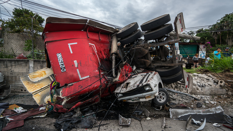A massive wreck of a truck that has crashed into a car