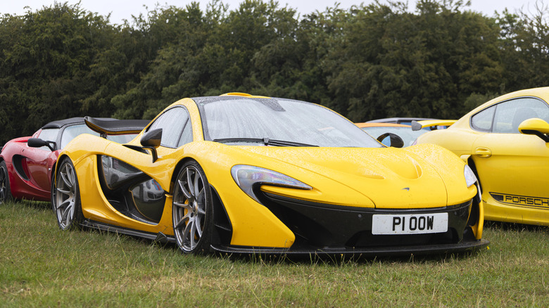 A yellow McLaren P1 parked on the grass for display