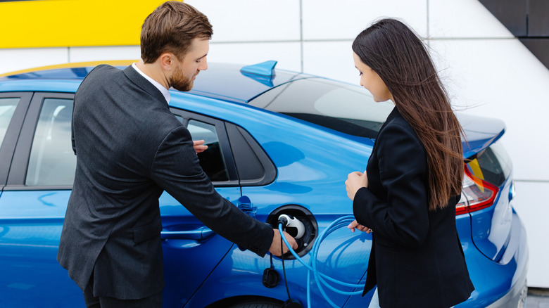 A man and woman looking at an EV being charged.