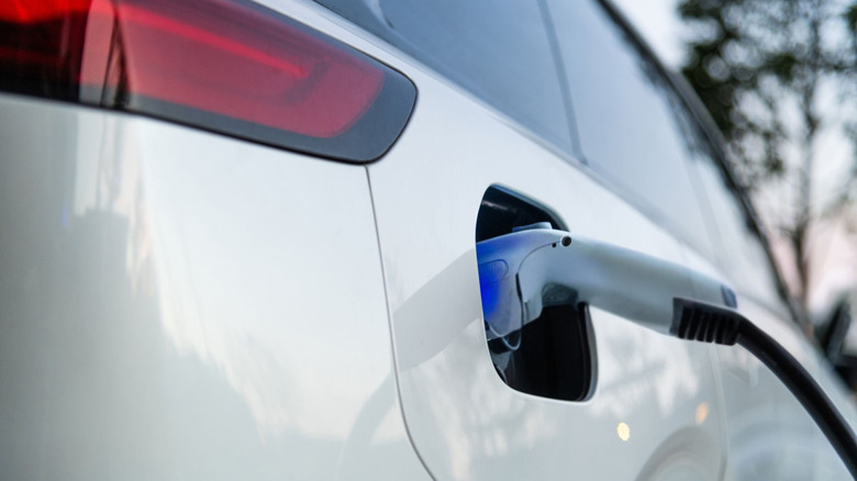 A charging cable connected to a white EV.