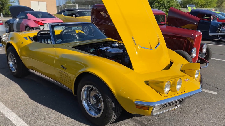 A side shot of a yellow 1971 Corvette LS6 with its hood open at a car show