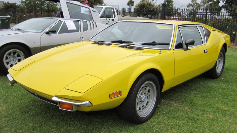 A yellow 1971 De Tomaso Pantera parked on grass at a car show