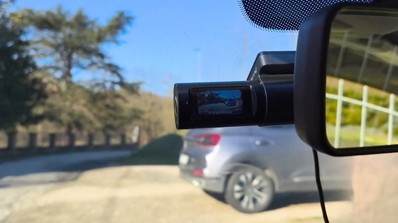 Cievie dash cam next to rear view mirror on car windshield