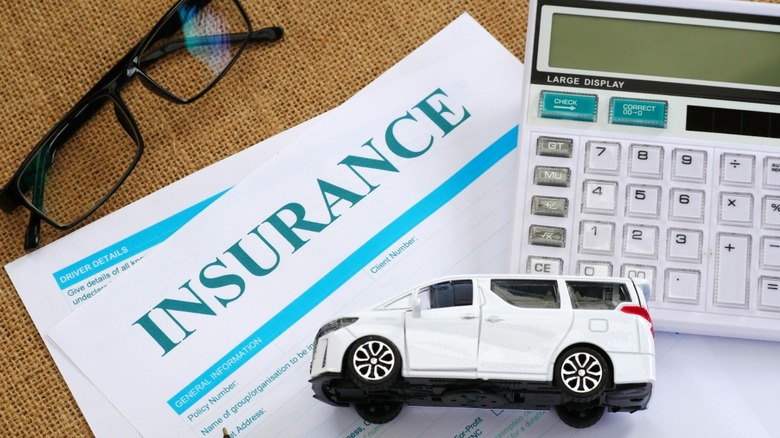 A toy SUV, calculator, and paper that reads "Insurance" at the top