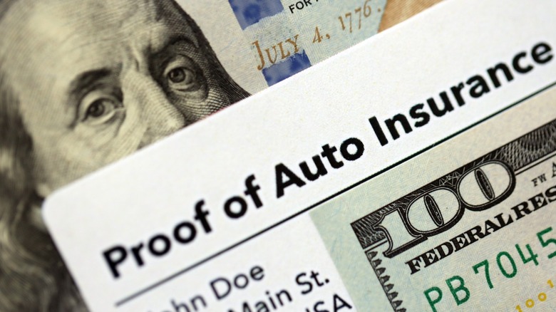 A $100 bill on top of proof of auto insurance