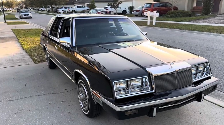 A 1987 Chrysler New Yorker in black parked on a sidewalk