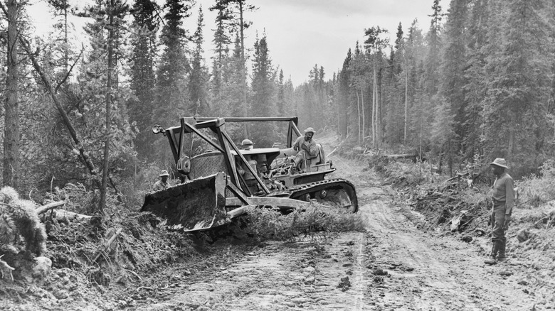 Workers using a bulldozer help build the Alaska Highway, also known as the Alaska-Canada or Alcan Highway, in 1942