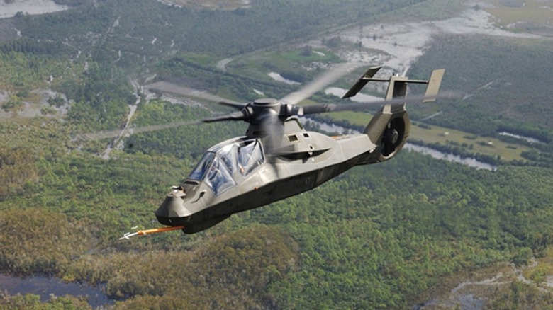 An RAH-66 Comanche prototype flying over a forested area