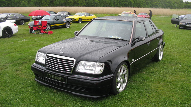 A black Mercedes-Benz 500E sits on a lawn.