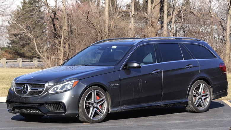A dark Mercedes-Benz E63 AMG Wagon sits in a lot.