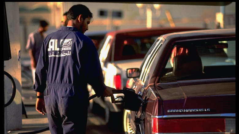 Gas station attendant fills up a car