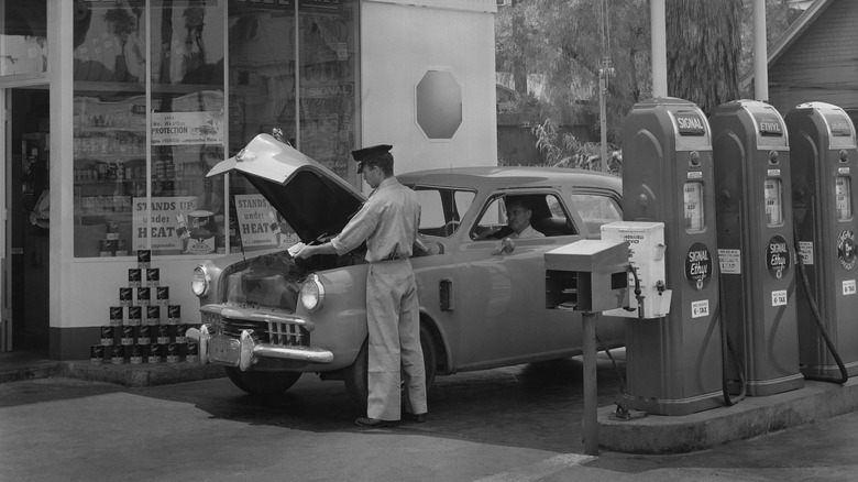 Gas station attendant checks a car's oil