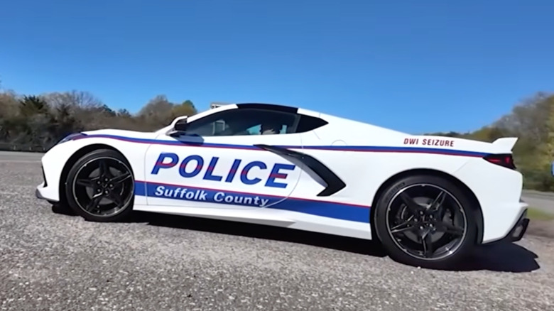 A side view of the white C8 Corvette coupe with its new livery parked in the median of a road