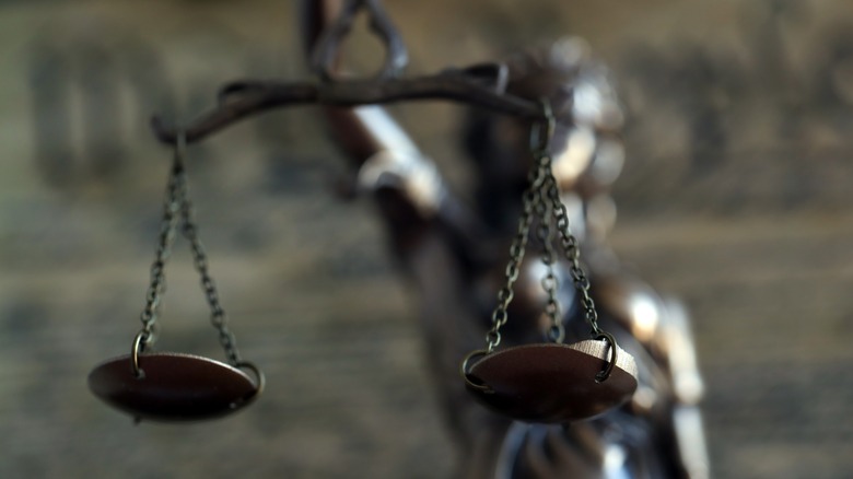 A close-up of Lady Justice's scales with the rest of the statue and the United States Constitution out of focus in background