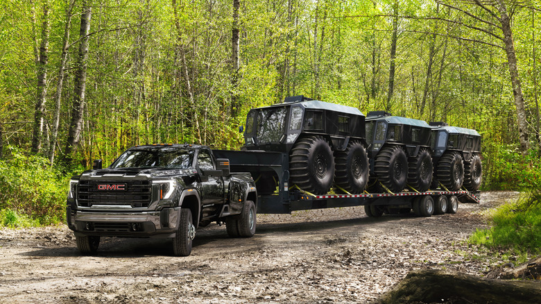 a black GMC Sierra 3500HD dually pulling a large flatbed trailer