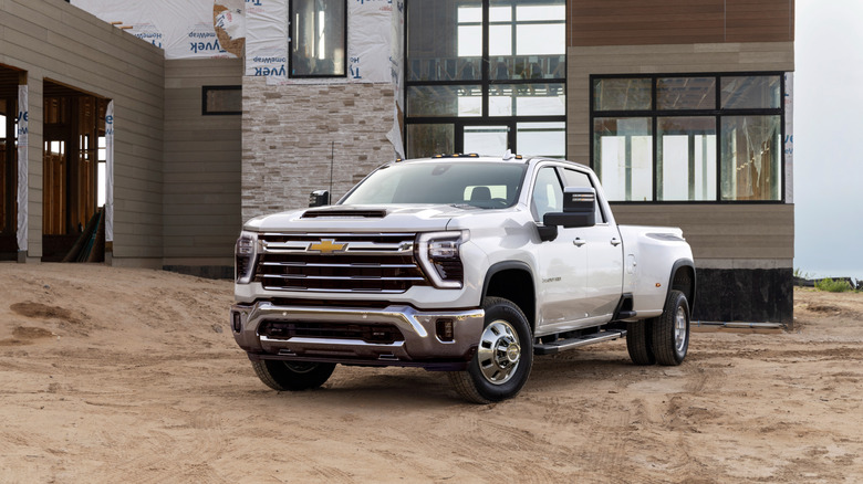 a white 2024 Chevrolet Silverado 3500HD dually parked in front of a residential development