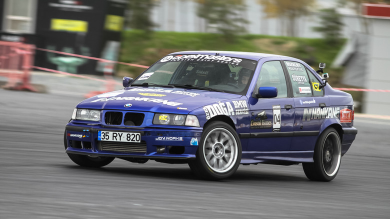 A blue E36-generation BMW 325i drift car at a competition.