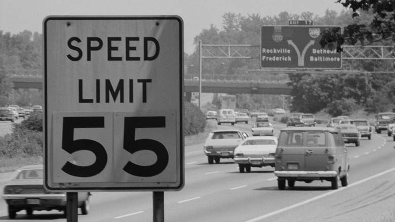 A 1977 55 mph speed limit sign along the Washington Beltway, with cars passing in the background.