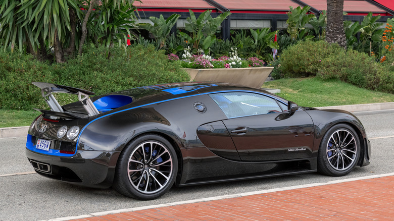 A rear three-quarter view of a dual tone black and blue Bugatti Veyron Super Sport driving through Monaco.