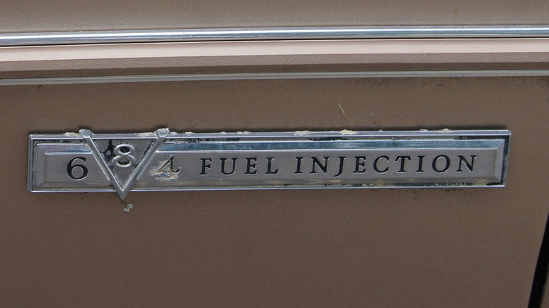A Cadillac V8-6-4 badge on the side of a brown car.