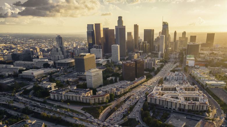 The sprawling metropolis of Los Angeles at sunset, with downtown sitting proudly in the middle surrounded by traffic on surrounding highways.