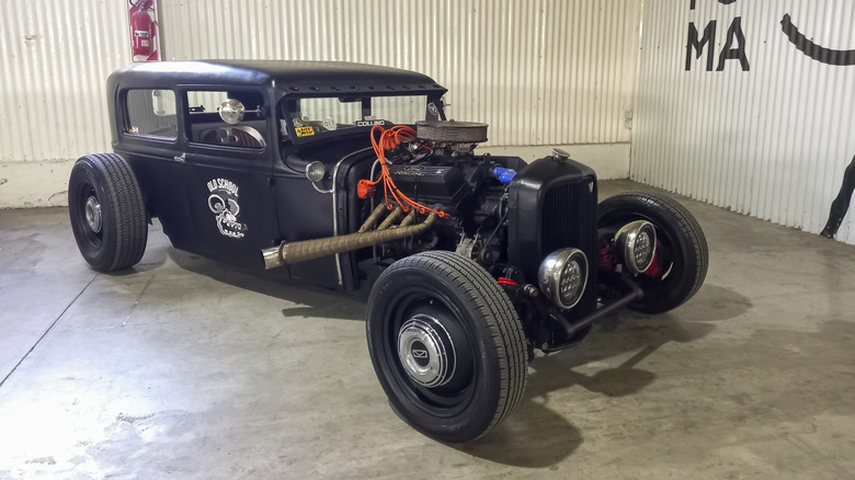 A black Ford V8 hot rod at a car garage